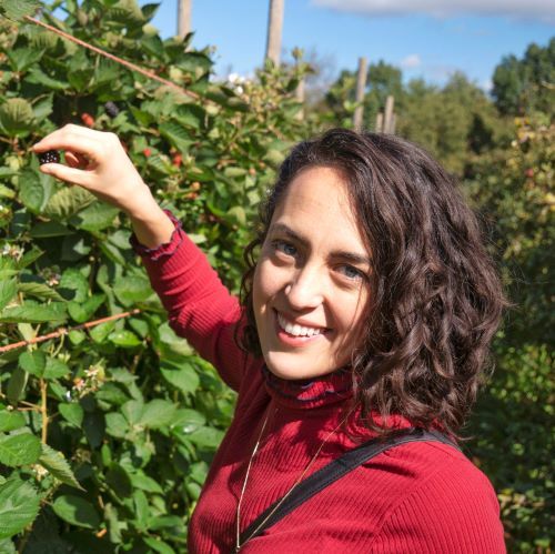 Maddie picking raspberries and smiling at the camera.